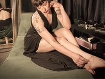 Dominatrix sits playing with her bare feet as she completes a BDSM scene negotiation