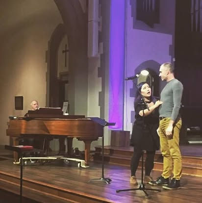 Vocal coach Rebecca Lam leading a live performance workshop for Universal Gospel Choir singers in Vancouver. She looks focussed while coaching stage presence, vocal technique, and emotional connection during a group masterclass.