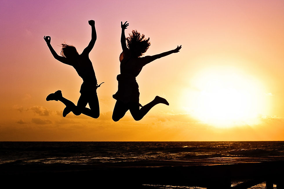 Two happy people jumping with sunset behind