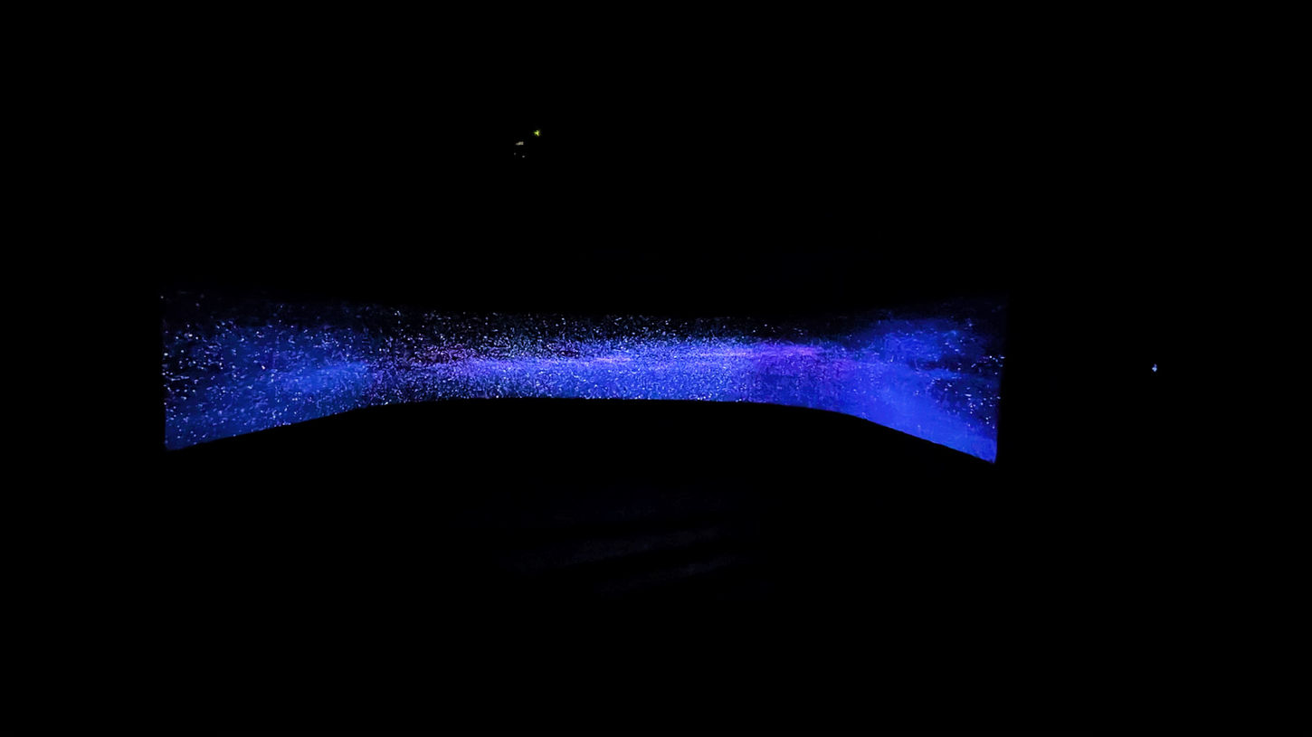 A large, curved projected image of a purple starry night sky.