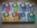 Eight colorful Game Boy Color boxes in various hues, arranged on a beige carpet, with visible branding text "Game Boy Color."