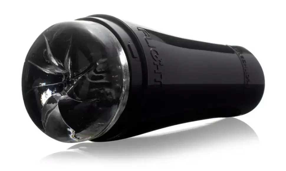 Black cylindrical object with transparent, textured top on a reflective surface. "Fleshlight" is visible in raised text on the side.