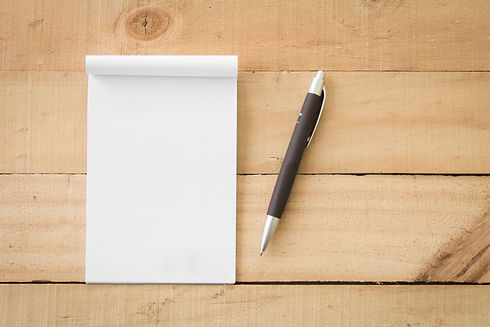 A blank notebook page and pen on wood office table. Top view with copy space..jpg
