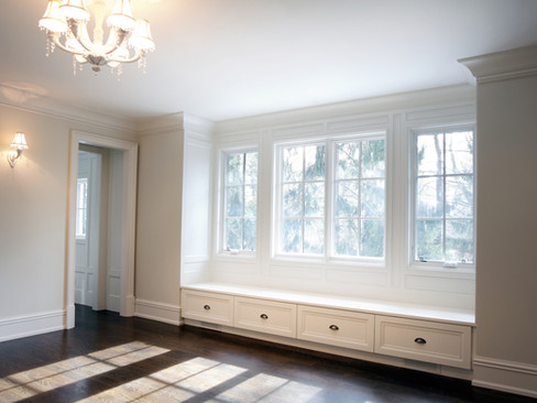 Salón blanco con ventanales por los que entra el sol