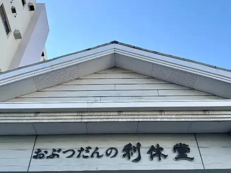 長崎市の仏壇・仏具店「おぶつだんの利休堂」の店舗外観。建物上部に店名が見え、青空の下にたたずむ店舗の様子。