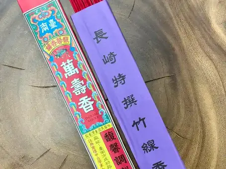 木の温もりが感じられる「おぶつだんの利休堂」の店内のテーブルに、紫色のパッケージの「長崎特撰竹線香」と、赤色のパッケージの「萬壽香」が並んで置かれている。