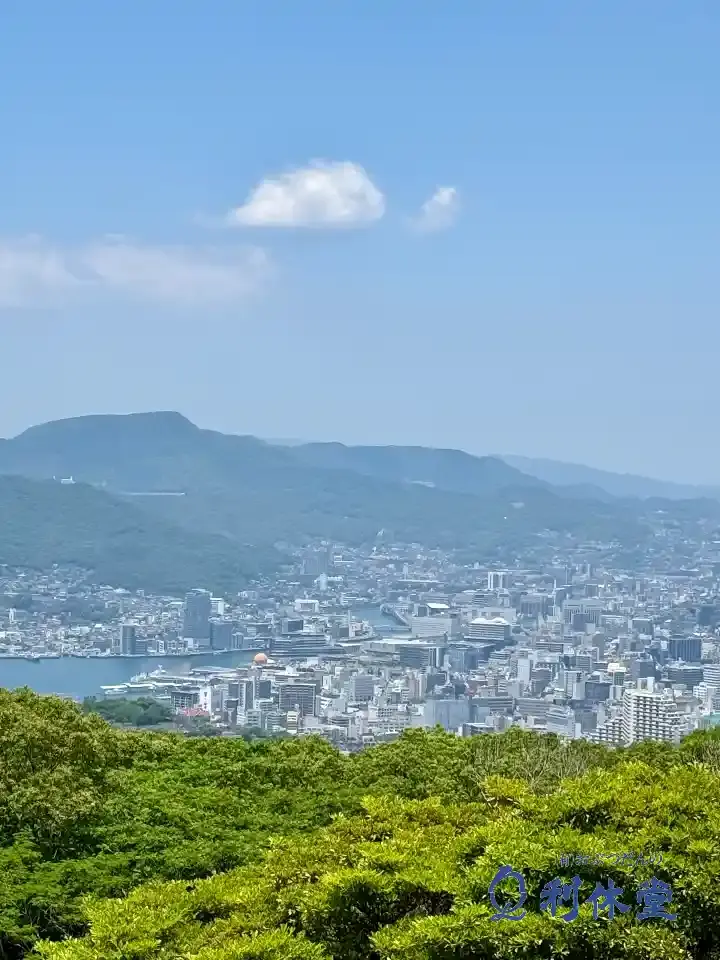 長崎市にある唐八景(とうはっけい)からの美しい眺望。中央にそびえる稲佐山をはじめ、長崎港や長崎の街並み、一帯が一望できる絶景のロケーション。子供と一緒に遊びに行きたくなる、長崎市内を広く見渡せる人気の映えスポット。