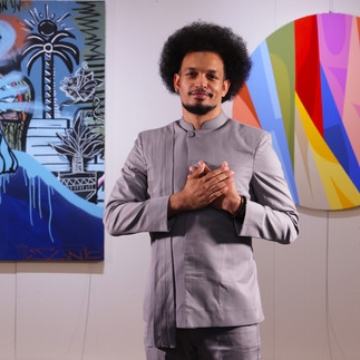 Composer Joe Williams standing in front of colorful wall art, wearing a neru jacket