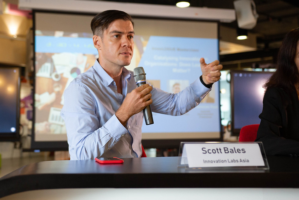 Scott Bales, a **Top Digital Transformation Expert** from Innovation Labs Asia, speaks at a conference with a microphone, gesturing to the audience.