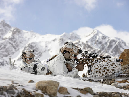 Zwei Soldaten liegen im Schnee auf einer Bergkuppe und observieren das Gelände. Sie sind mit Multicam Alpine getarnt.