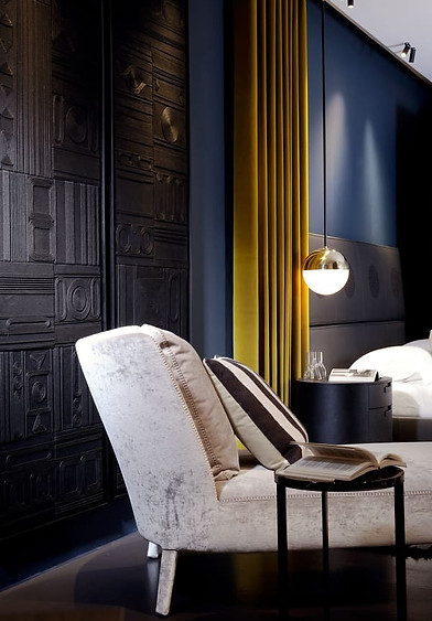 a luxury interior design space showing a bedroom with a bed, a chair, and a lamp delivered, a project delivered by sans compromis agency