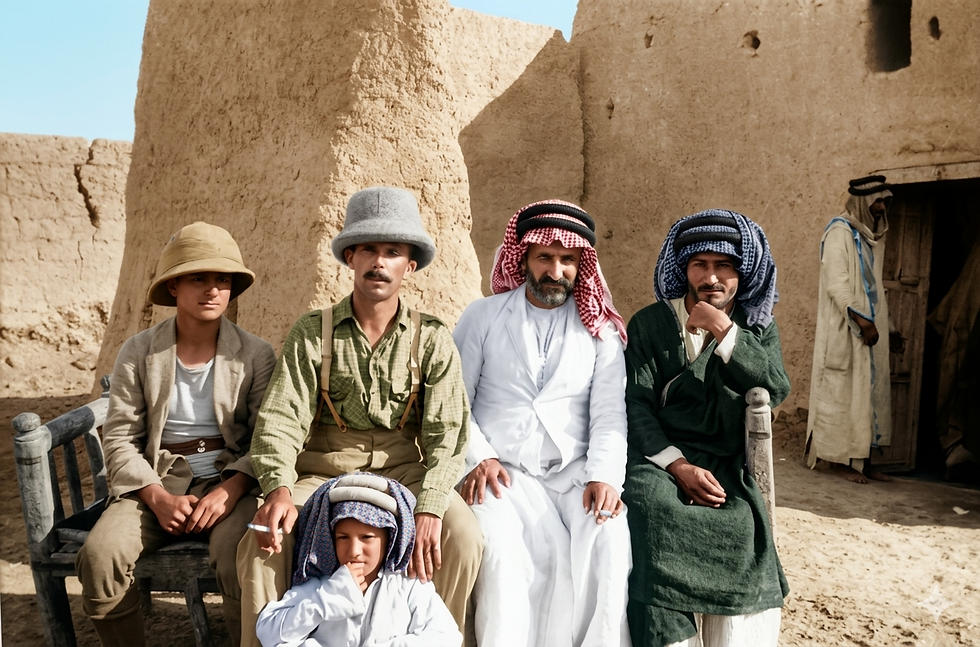 Five men and a child in traditional dress sit outside mud-brick buildings under bright sun, looking at the camera.