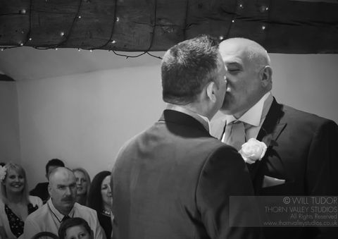 Two grooms share a kiss during ceremony. WEDDING PHOTOGRAPHY with Thorn Valley Studios.