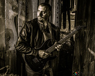 Man playing electric guitar, leather jacket, wooden background, PORTRAITS, Thorn Valley Studios.