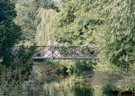 Two brides face each other on a bridge over a river in summer