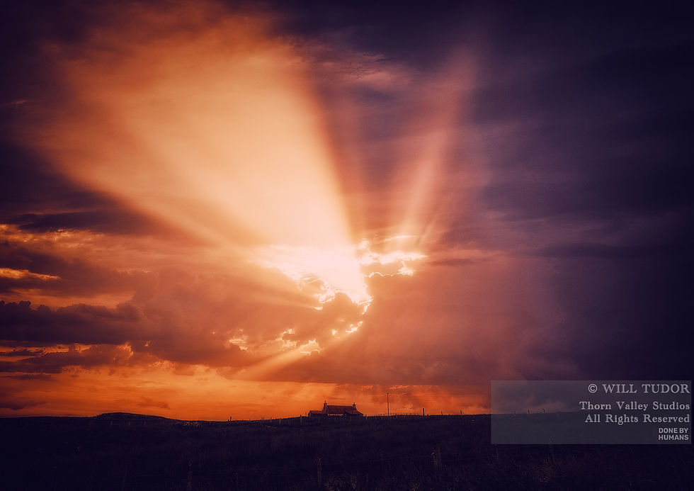 Dramatic orange sunset with rays bursting through dark clouds over a rural field and small house; watermark text in lower right.