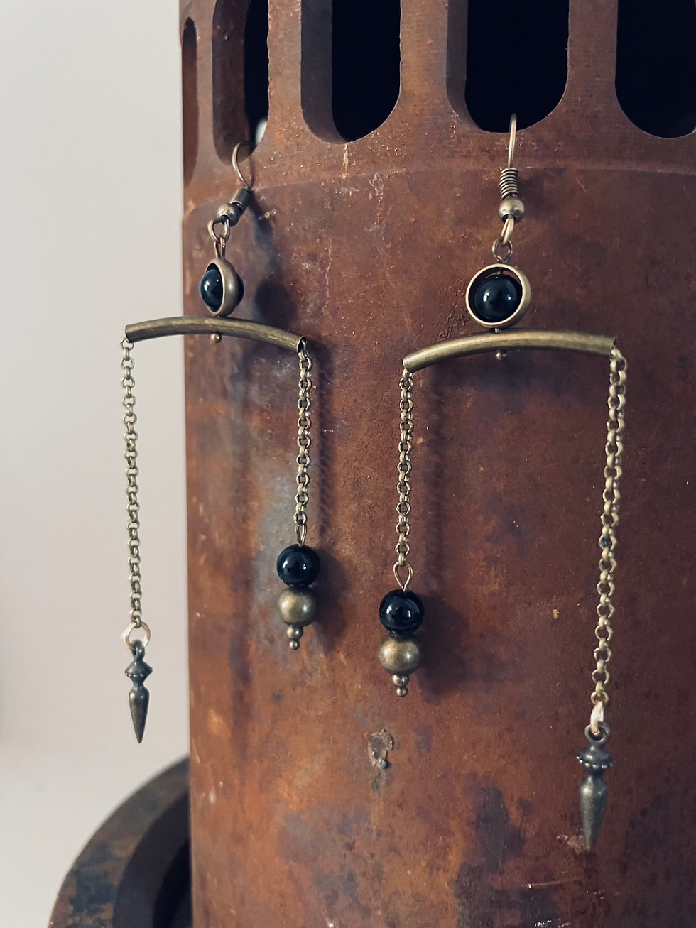 Thumbnail: Brass and onyx earrings dangle from a rusted pipe