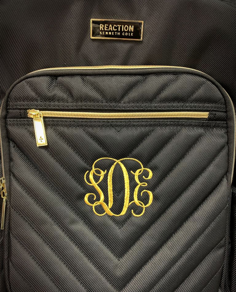 Black quilted Reaction backpack with gold zipper and monogram embroidery