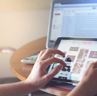 Hands holding a tablet, pinching fingers to zoom in on the screen.