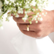 Handmade hammered solid gold wedding band worn on hand holding white flowers, elegant minimalist jewellery made in Nottingham