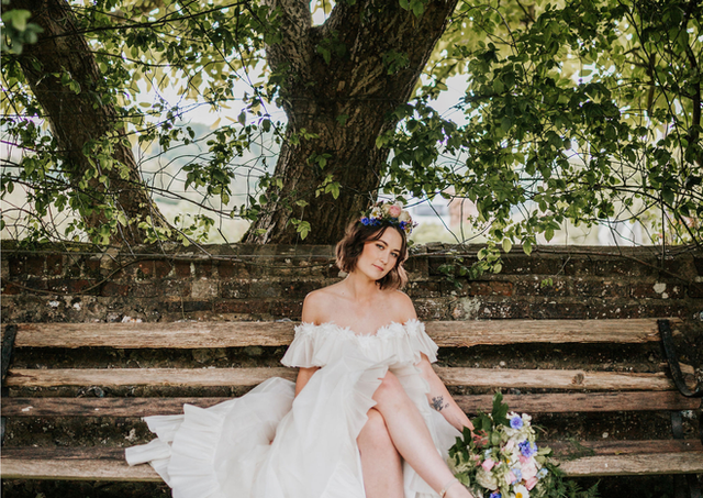 Bride with soft waves sitting on a rustic garden bench at Upwaltham Barns.