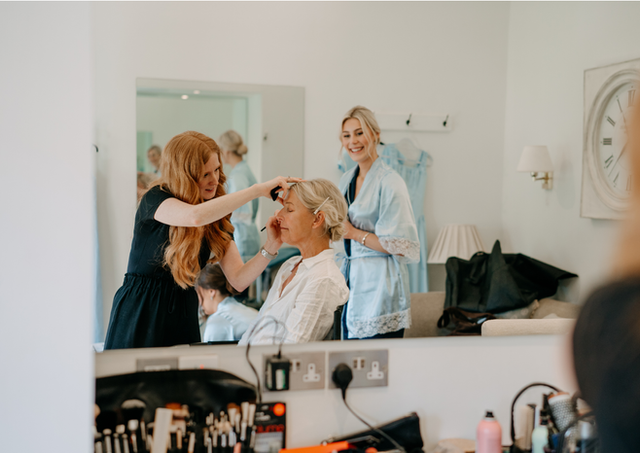 Bridesmaid in the makeup chair getting ready for Rosalie's wedding at Farbridge Barn, styled by Toni Todd