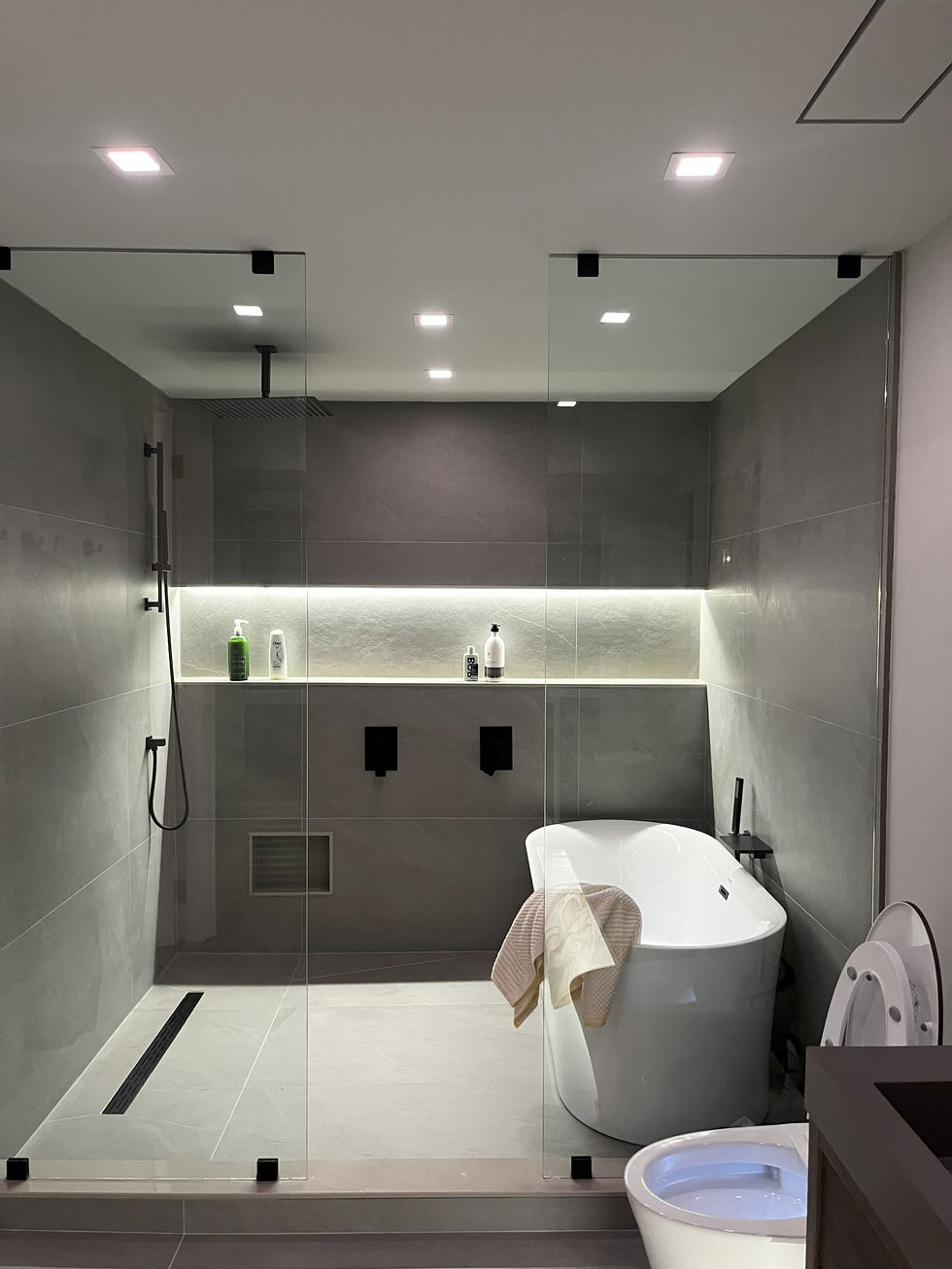 Grey stand-up shower with LED under-glow lighting beneath built-in shower niche | Luxury bathroom design by Pearl Knstructions