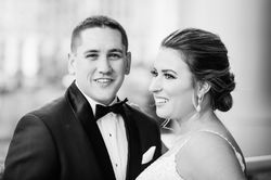A bride looks over her shoulder smiling while the groom smiles directly at the camera.