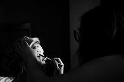 A dramatic look into a bride getting ready for her wedding day. She is getting eye shadow from a mak