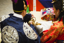 A groom pours tea for his bride during a traditional Korean wedding ceremony.