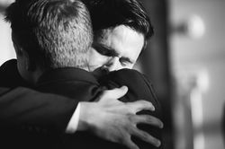 A sweet close-up moment of a groom crying and hugging his bestman after walking down the aisle.