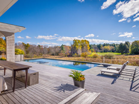 wood deck with pool overlooking an autumnal meadow.