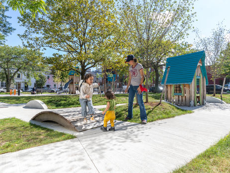 an adult with two children playing on a small walking bridge at a playground.