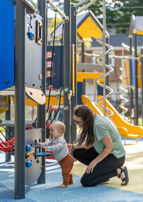 Woman and baby playing at a colorful new play structure at Stonehill Park - Crowley Cottrell LLC Landscape Architecture