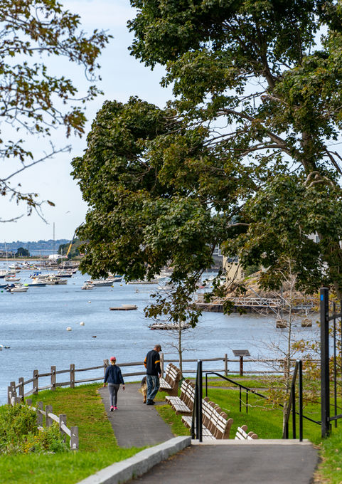 Visitors walk the path along the edge of the rocky peninsula at Fort Sewall with the harbor beyond - Crowley Cottrell LLC Landscape Architecture