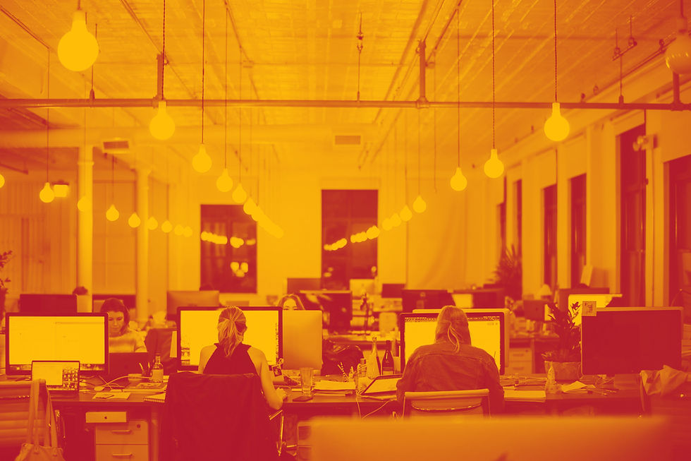 Modern open-plan office with employees at their desks under glowing lightbulbs – symbolizing real-time culture analytics illuminating workplace sentiment.