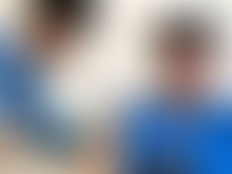 Jovem enfermeiro aplicando vacina em homem de meia idade com camisa azul e boné.