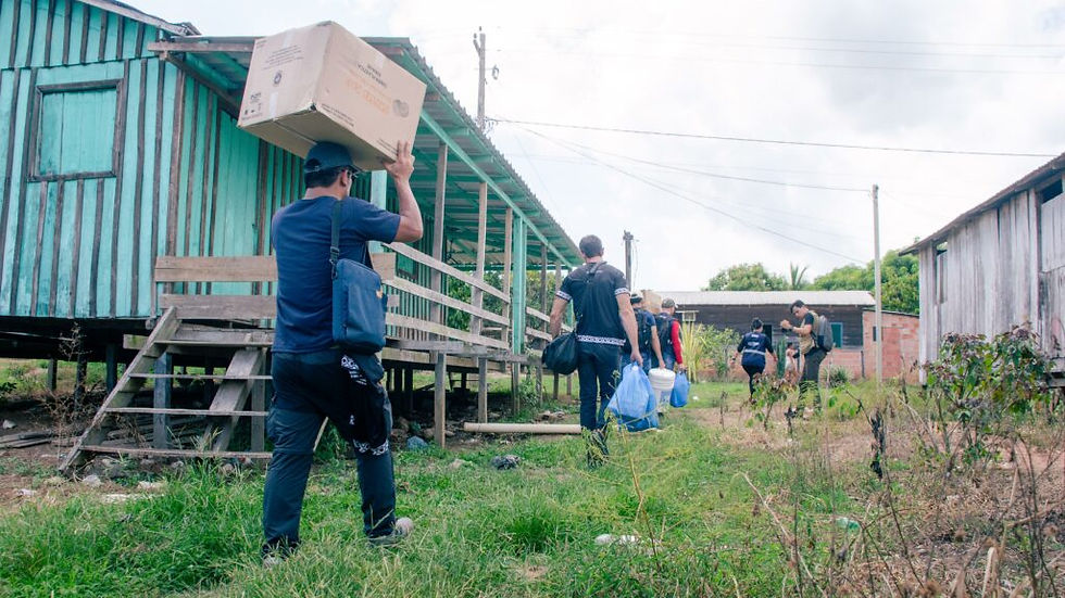 Voluntários carregando caixas e sacolas em comunidade indígena.