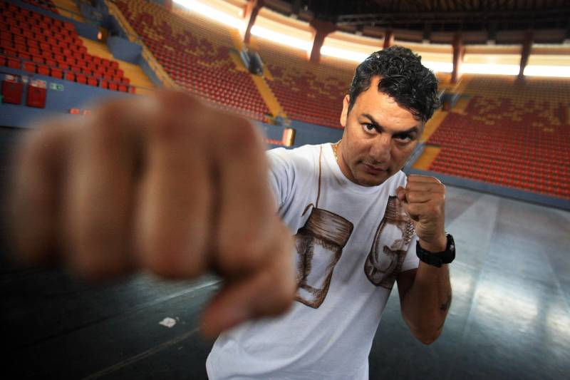 Acelino "Popó" de Freitas em posição de boxe como se tivesse lutando com a câmera, ao fundo quadra de futsal.