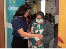 Mulher com papéis explicando para senhora informações sobre vacinação.