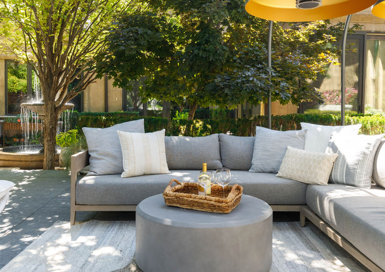 Outdoor living space with sofa, trees, greenery and decor