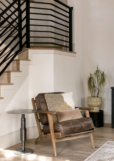 Stairway of a home leading upstairs and an accent chair and table