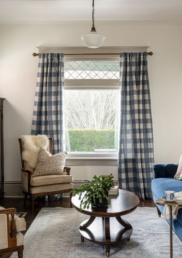 Living room space with couch, 2 chairs and a coffee table. the furniture brings in more vintage and antique vibes with blues and dark woods