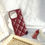 Thumbnail: A luxurious burgundy phone case with a diamond-shaped quilted pattern, displayed alongside makeup products and a black purse.