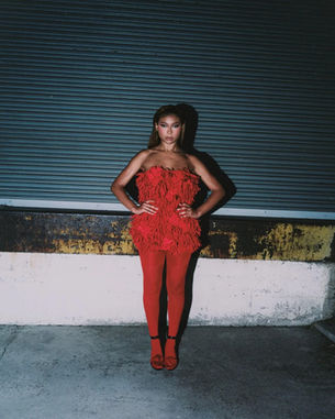 Sierra Capri wearing Giseli Dias floral sandals with a red mini dress and matching tights for Numéro Netherlands.