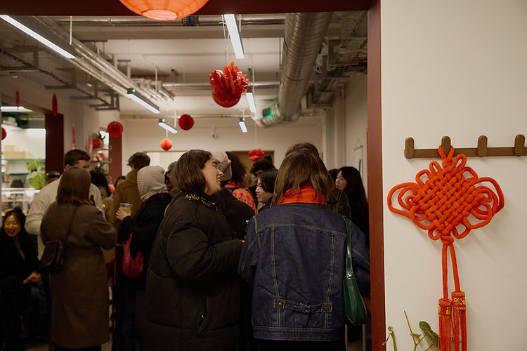 crowd in a room at a party with red lunar new year decorations hanging around them