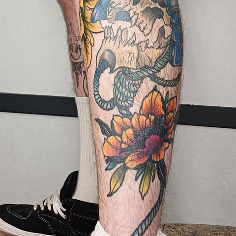 a man has a tattoo of a skull and flowers on his leg