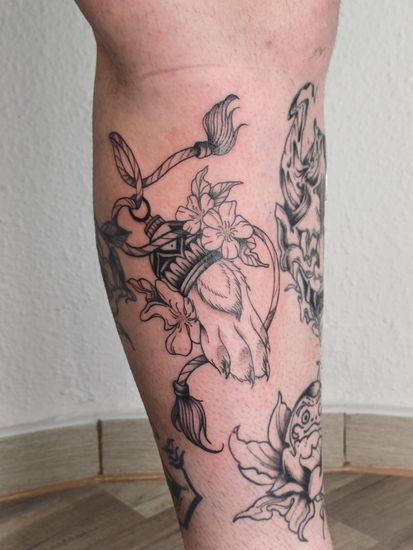 a tattoo on a person 's leg shows a paw and flowers