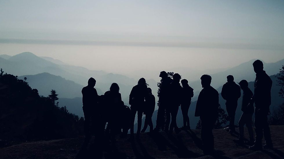 A silhouette of people standing on a mountain with a misty background.