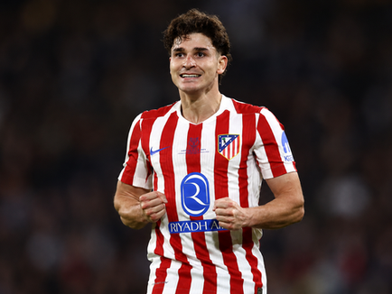An Atlético Madrid player in the club's red and white striped shirt holding up the crest